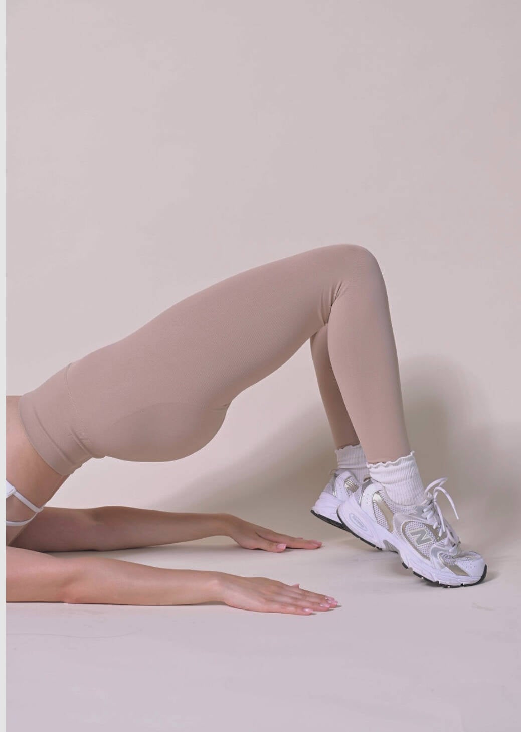 Studio member in a maroon one-piece kneeling on a cream studio backdrop